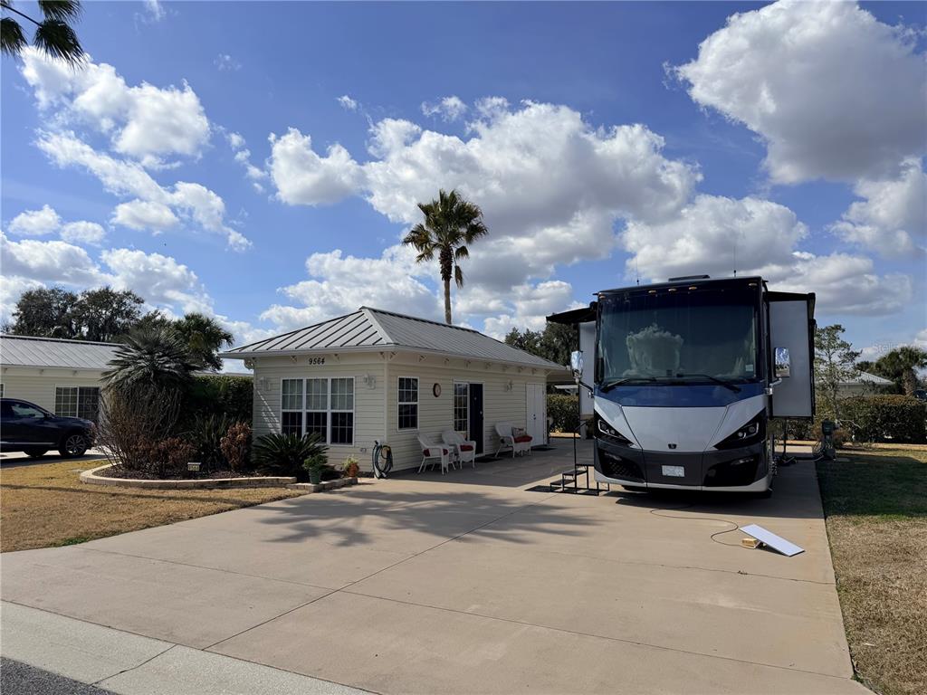 A small house with a metal roof sits next to a large RV on a driveway — 9564 SE 47TH WAY, WEBSTER, FL
