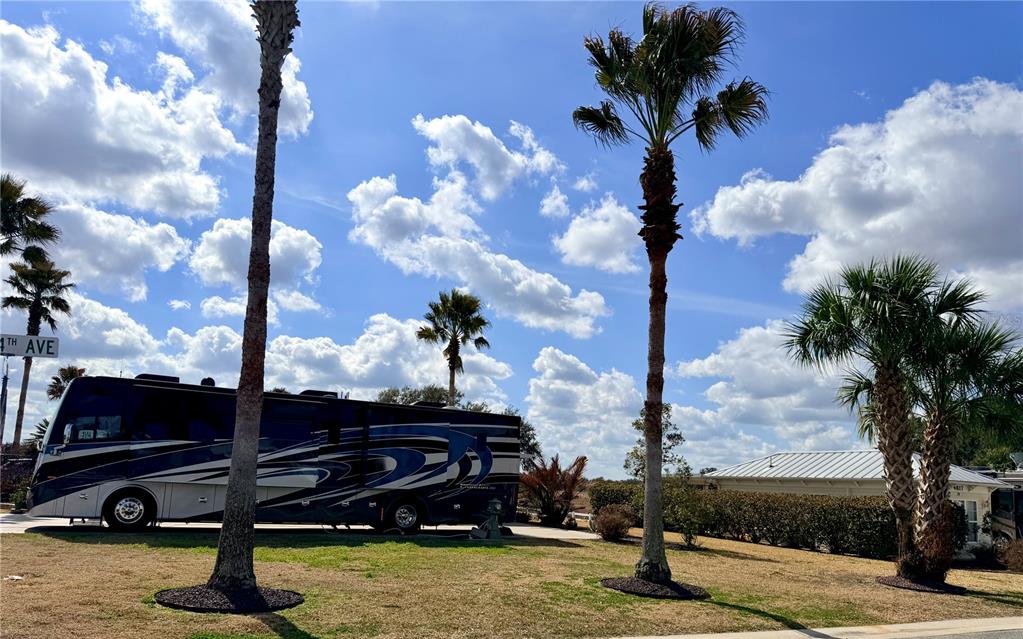 A large recreational vehicle is parked on a grassy lot with palm trees — 9564 SE 47TH WAY, WEBSTER, FL