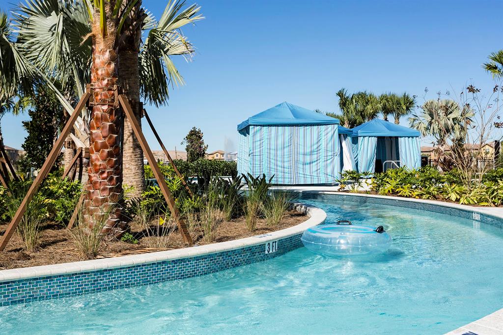 A lazy river pool with a clear inner tube and blue cabanas under a clear sky — 2431 DUBAI STREET, KISSIMMEE, FL