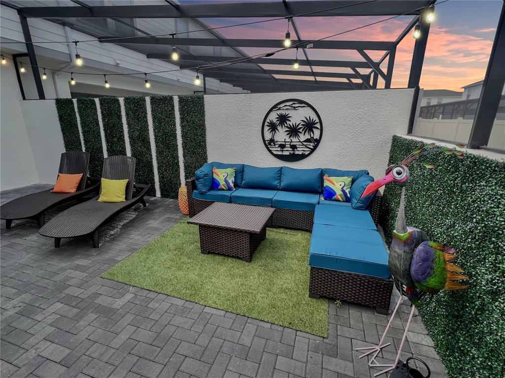 A patio features a sectional sofa, two lounge chairs, artificial turf, and a decorative metal bird — 2431 DUBAI STREET, KISSIMMEE, FL