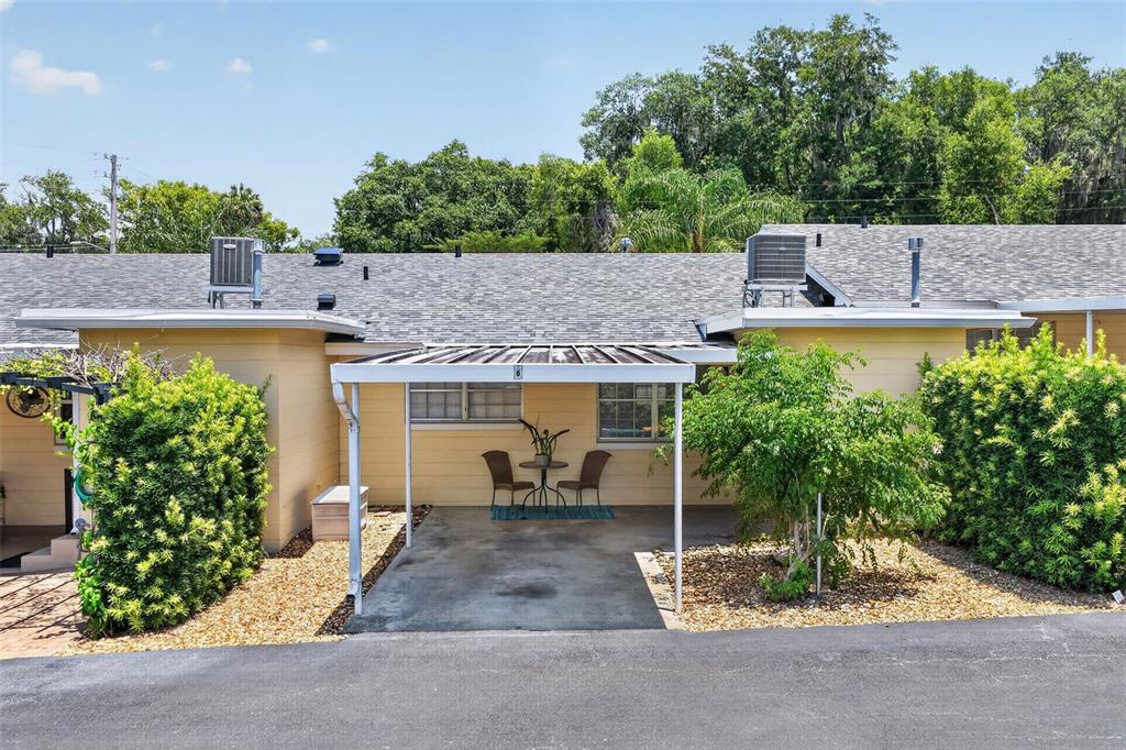 A single-story house exterior features a covered carport with a small table and two chairs — 445 S GRANDVIEW STREET UNIT 8, MOUNT DORA, FL