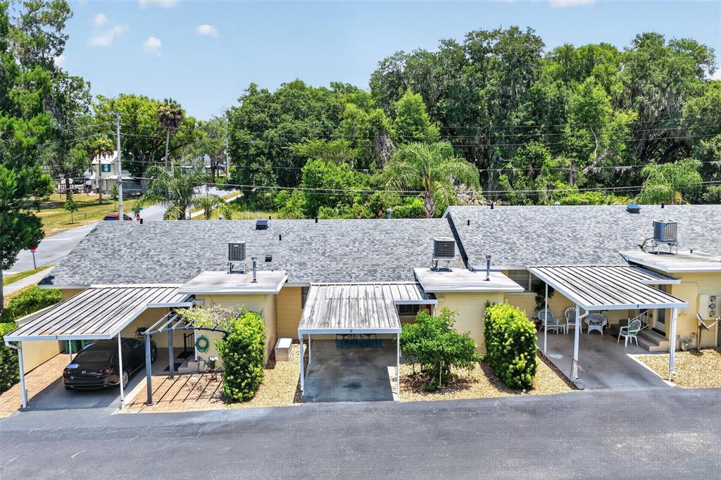 An aerial view shows a single-story building with three carports and a shingled roof — 445 S GRANDVIEW STREET UNIT 8, MOUNT DORA, FL