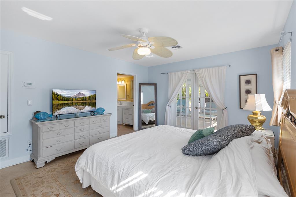 A bedroom features a white dresser, a bed with white bedding, and a ceiling fan — 7860 HOLIDAY DRIVE, SARASOTA, FL