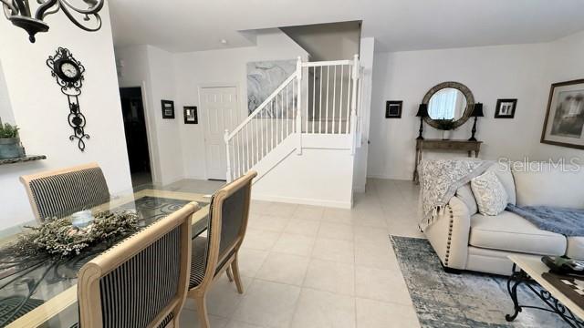A dining area with a glass table and chairs sits adjacent to a living room staircase — 8074 MURANO CIRCLE, PALM BEACH GARDENS, FL