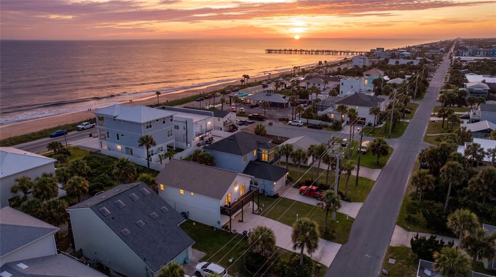 An aerial view of a coastal neighborhood at sunset with houses near a beach and pier — 712 CENTRAL AVE N, FLAGLER BEACH, FL