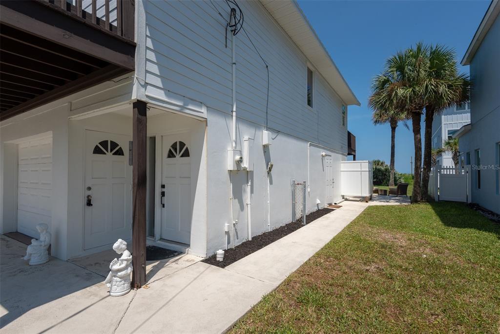 The exterior of a white house features two entry doors, a garage, and a lawn — 712 CENTRAL AVE N, FLAGLER BEACH, FL