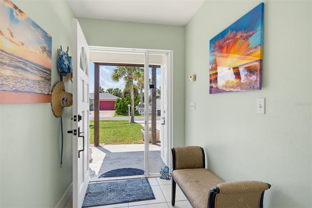An entryway with light green walls, a bench, wall art, and an open door to outside — 712 CENTRAL AVE N, FLAGLER BEACH, FL