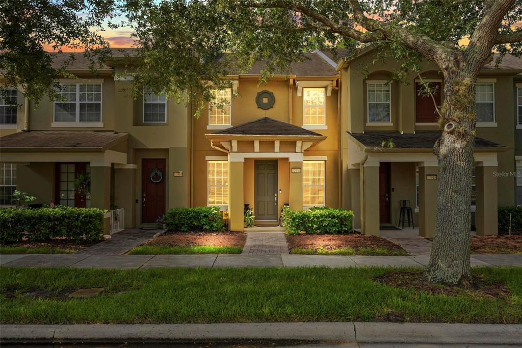 A row of three attached townhouses features tan stucco facades, dark doors, and front landscaping — 12914 VENNETTA WAY, WINDERMERE, FL