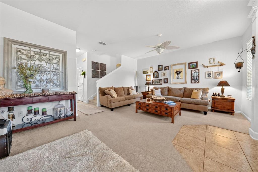 A living room features beige carpeting, two brown sofas, a wooden coffee table, and wall decor — 12914 VENNETTA WAY, WINDERMERE, FL