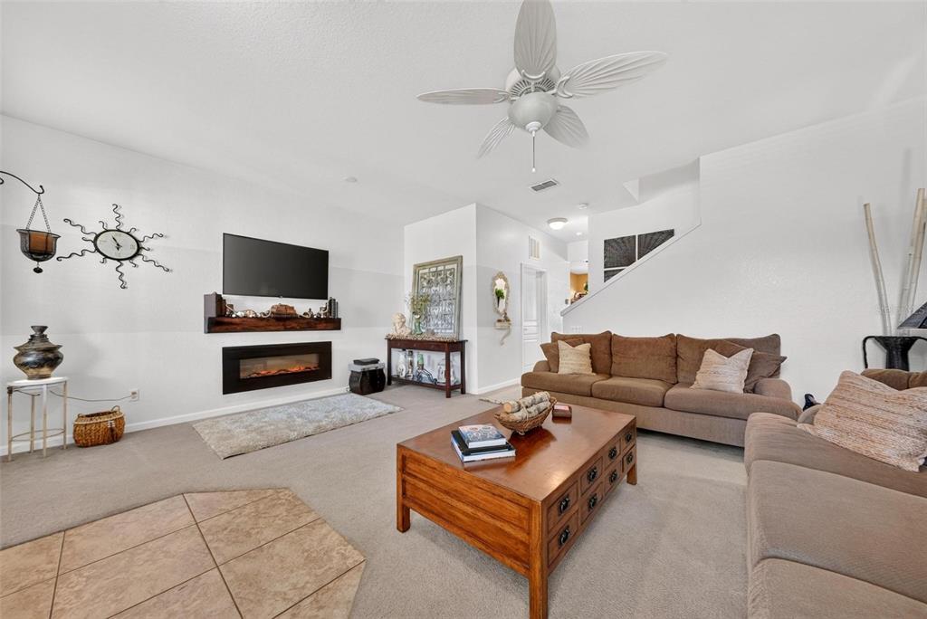 A living room features a fireplace, wall-mounted television, brown sofas, and a wooden coffee table — 12914 VENNETTA WAY, WINDERMERE, FL