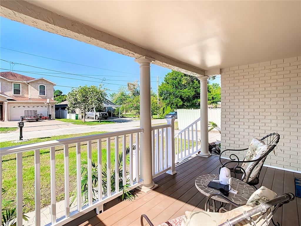 A covered porch features white railings, two support columns, a tiled table, and chairs — 3321 W AILEEN STREET, TAMPA, FL