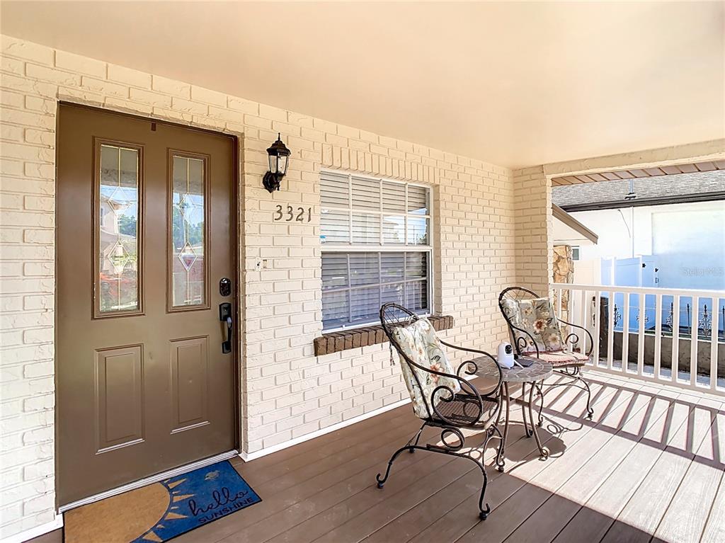 A covered front porch features a brown door, white brick walls, and two patio chairs — 3321 W AILEEN STREET, TAMPA, FL