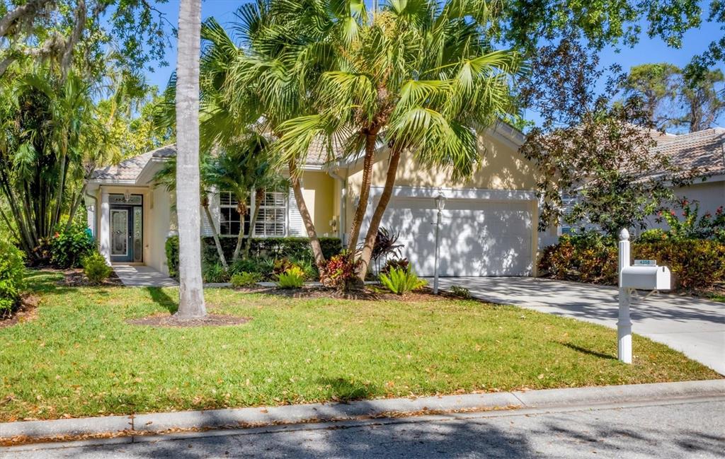 A single-story house with a white garage door, palm trees, and a front lawn — 4358 MIRABELLA CIRCLE, BRADENTON, FL
