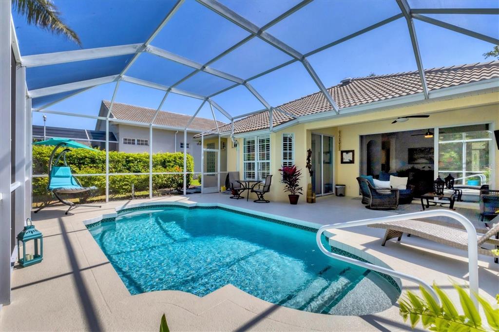 A screened-in patio features a swimming pool, outdoor seating, and a view of the house — 4358 MIRABELLA CIRCLE, BRADENTON, FL