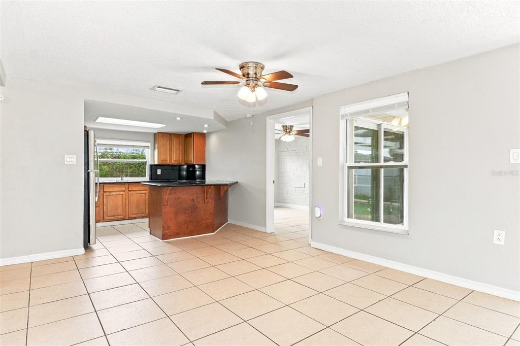 A kitchen with wood cabinets and a breakfast bar opens into a tiled dining area — 7235 WESTWIND DRIVE, PORT RICHEY, FL