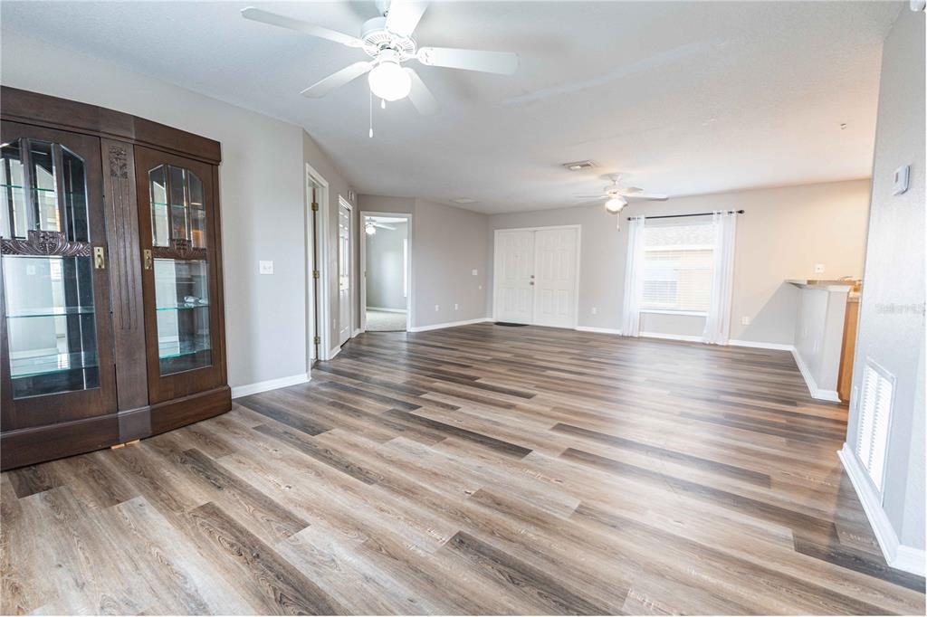 A spacious living area features wood-look flooring, two ceiling fans, and a dark wood cabinet — 3534 COUNTY ROAD 230C, WILDWOOD, FL