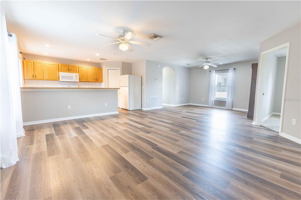 An open-concept living area with wood-look flooring, a kitchen with light wood cabinets, and ceiling fans — 3534 COUNTY ROAD 230C, WILDWOOD, FL
