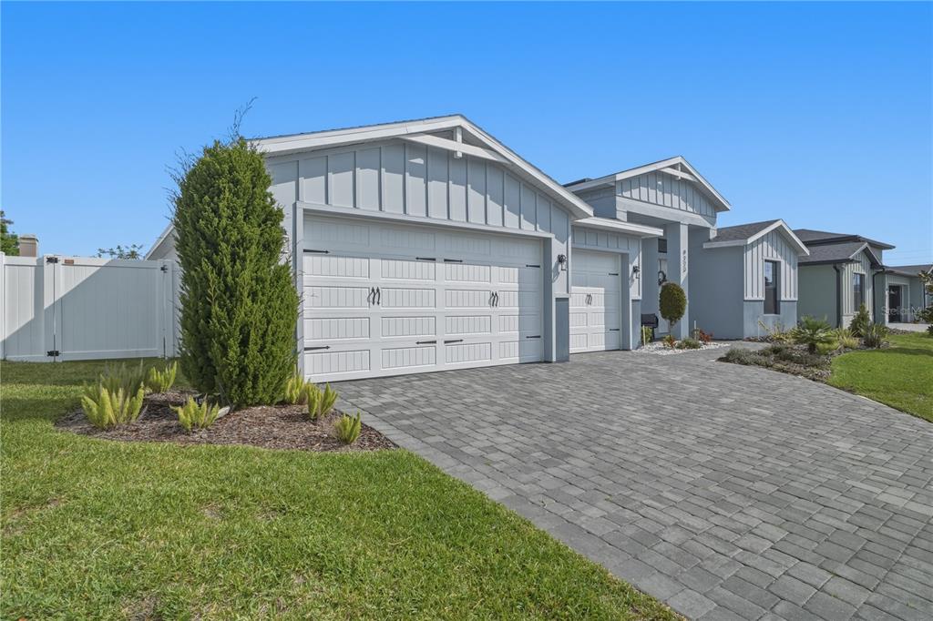 A light blue house with a three-car garage and a paved driveway under a blue sky — 9223 EAGLES PERCH PLACE, ORLANDO, FL