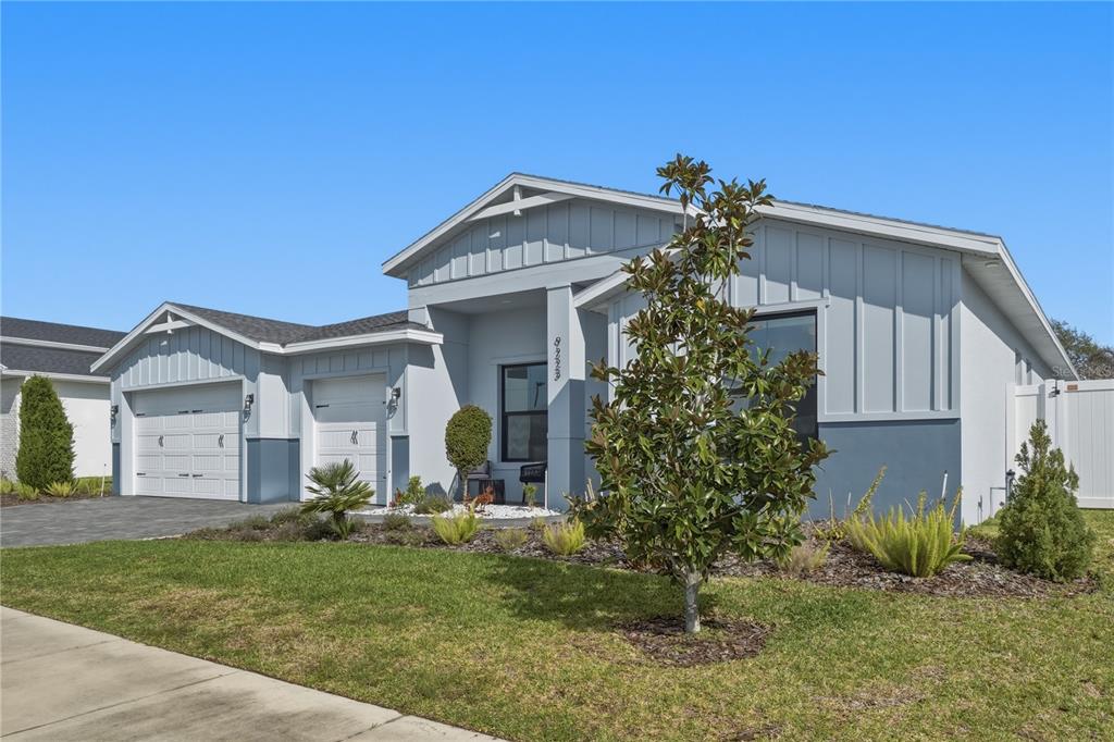 A single-story house with a gray exterior, white garage doors, and a landscaped front yard — 9223 EAGLES PERCH PLACE, ORLANDO, FL