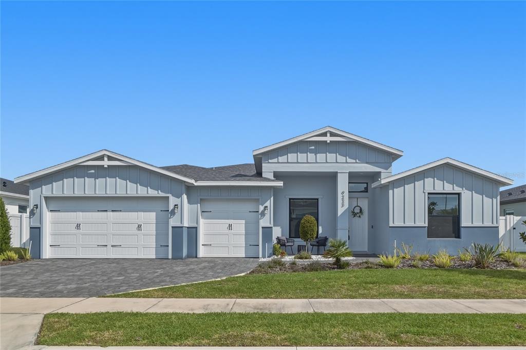 A single-story house features a two-car garage, light blue board-and-batten siding, and a paved driveway — 9223 EAGLES PERCH PLACE, ORLANDO, FL