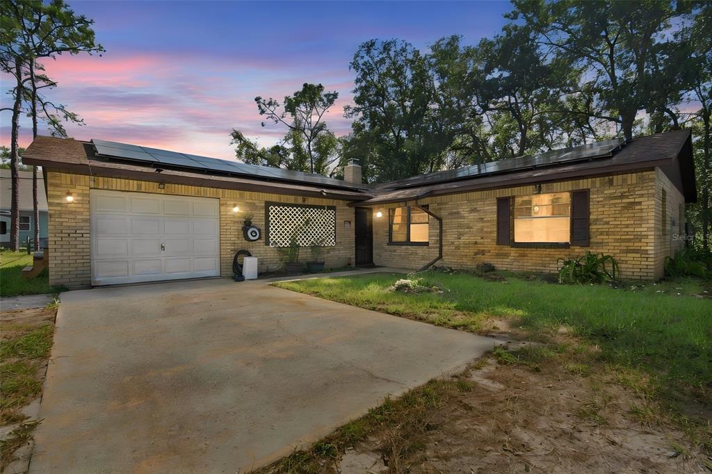 A single-story brick house with a garage, solar panels, and a concrete driveway — 7059 JUNIPER AVENUE, WEBSTER, FL