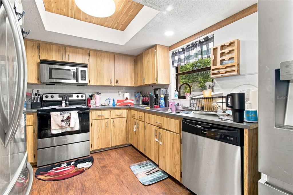 A kitchen with wood cabinets, stainless steel appliances, and a wood-paneled tray ceiling — 7059 JUNIPER AVENUE, WEBSTER, FL