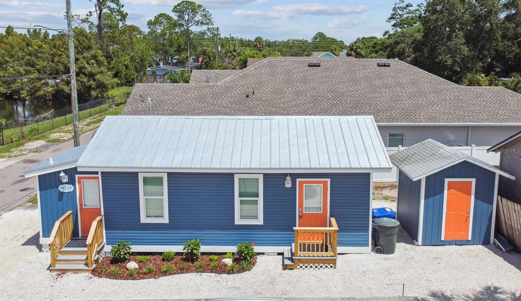 A blue house with a metal roof and orange doors sits next to a matching shed — 602 1/2 SKINNER BOULEVARD, DUNEDIN, FL