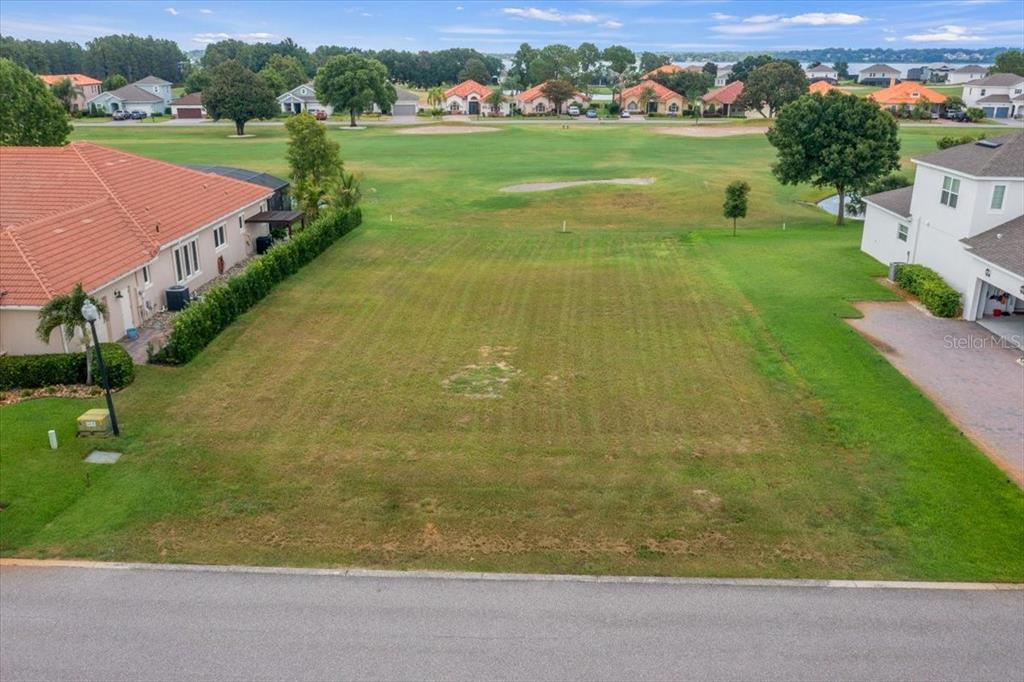 An aerial view shows a vacant residential lot situated between two houses on a golf course — LIVE OAK DRIVE, TAVARES, FL