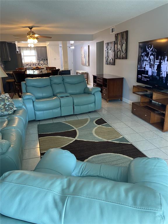 A living room features light blue leather sofas, a patterned area rug, and tile flooring — 5555 GULF BOULEVARD UNIT 104, ST PETE BEACH, FL