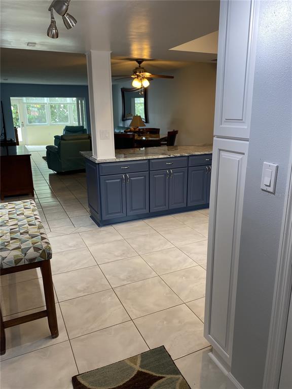 A kitchen island with blue cabinets and a stone countertop sits in a tiled room — 5555 GULF BOULEVARD UNIT 104, ST PETE BEACH, FL