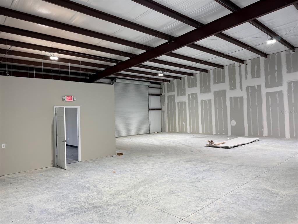 An unfinished warehouse space features a concrete floor, exposed steel beams, and drywall panels — 5741 S PINE AVENUE, OCALA, FL