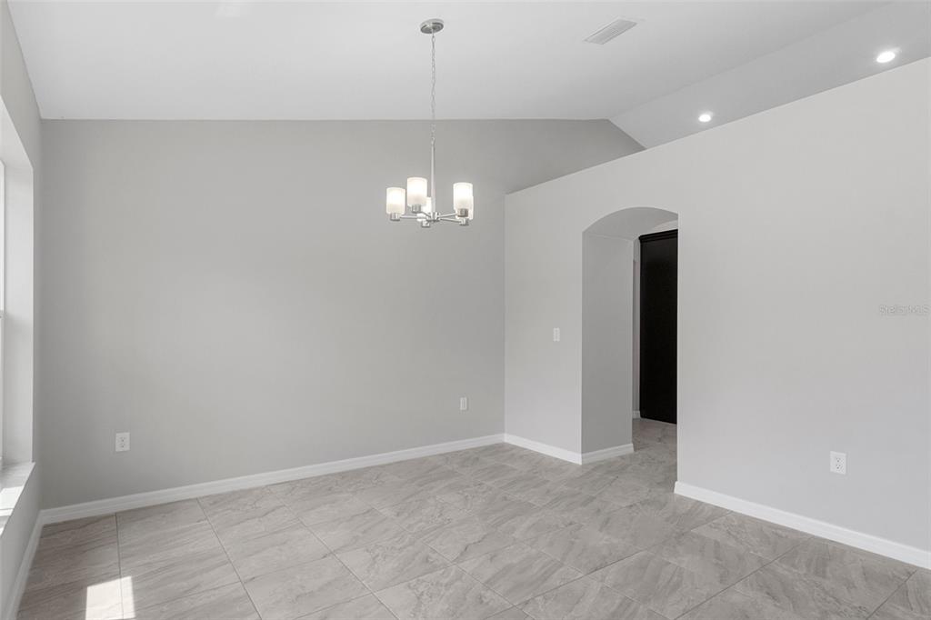 A dining room with light gray walls, tile flooring, and a modern chandelier — 12085 MANASSAS AVENUE, WEEKI WACHEE, FL