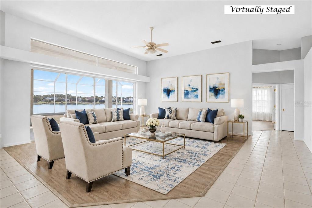 A living room with tile floors, a ceiling fan, and large windows overlooking a lake — 8911 RIVERLACHEN WAY, RIVERVIEW, FL