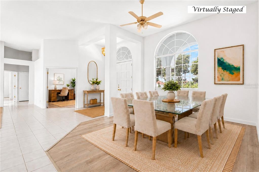 A dining room with a glass-top table, beige chairs, and a large arched window — 8911 RIVERLACHEN WAY, RIVERVIEW, FL