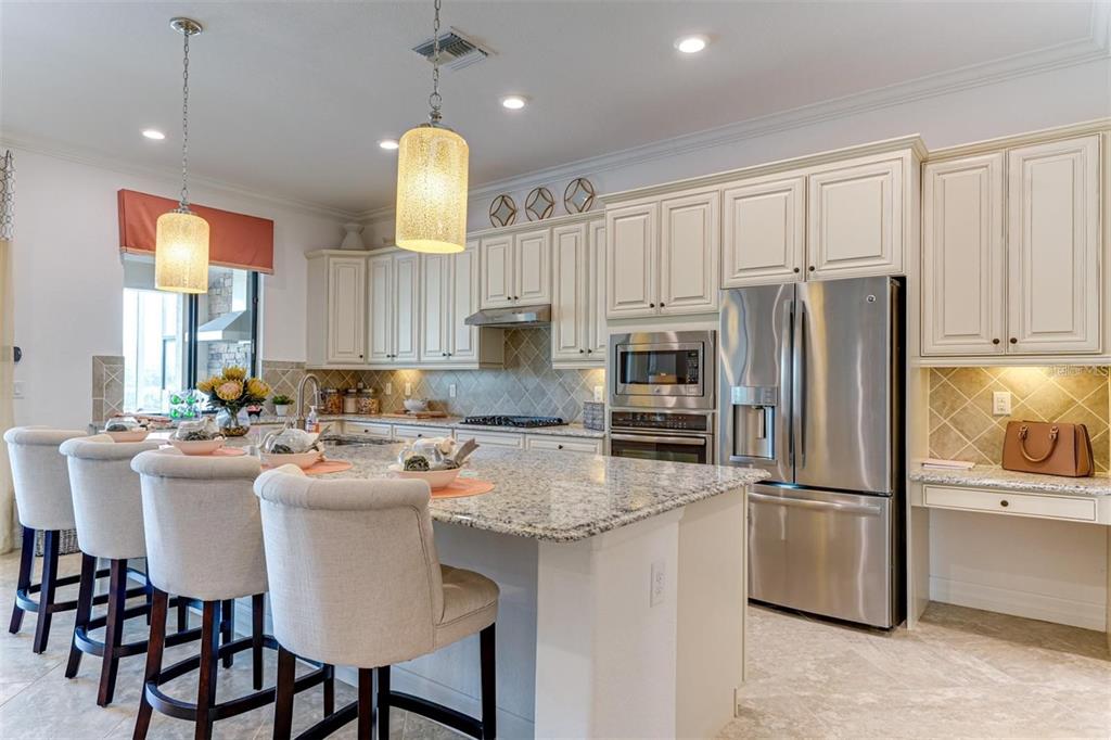 A kitchen with cream cabinets, granite countertops, a large island, and stainless steel appliances — 5803 CESSNA RUN, BRADENTON, FL