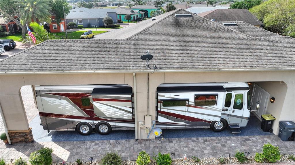 A large recreational vehicle is parked under a covered carport attached to a residential home — 416 MOTORCOACH DRIVE S, POLK CITY, FL