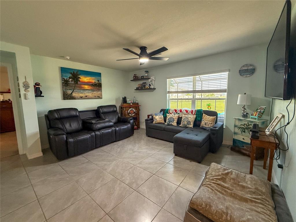 A living room features tile flooring, two sofas, a ceiling fan, and a wall-mounted television — 4120 QUIET RAIN COURT, PALMETTO, FL