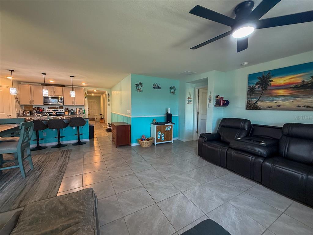 A living room with tile floors and a kitchen with bar seating in the background — 4120 QUIET RAIN COURT, PALMETTO, FL