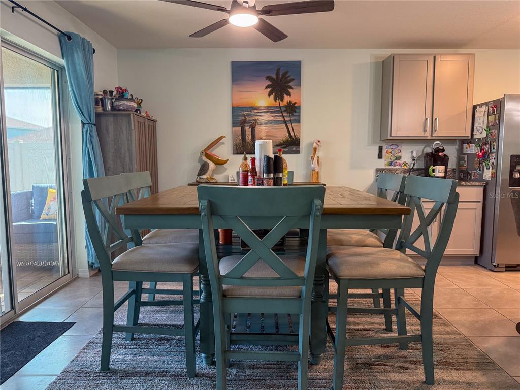 A dining area features a wooden table with blue chairs, a ceiling fan, and wall art — 4120 QUIET RAIN COURT, PALMETTO, FL