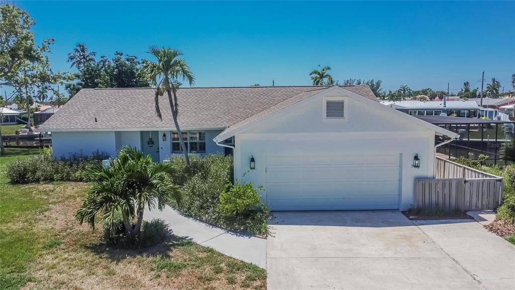 A single-story house with a white exterior, a two-car garage, and a palm tree — 5016 MANGROVE POINT ROAD, BRADENTON, FL