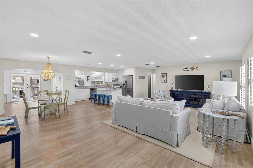 A swimming pool sits inside a screened-in patio area next to a white house — 5016 MANGROVE POINT ROAD, BRADENTON, FL