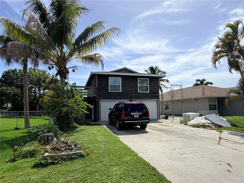 A two-story house with dark exterior sheathing, a two-car garage, and a palm tree — 125 4TH STREET, NAPLES, FL