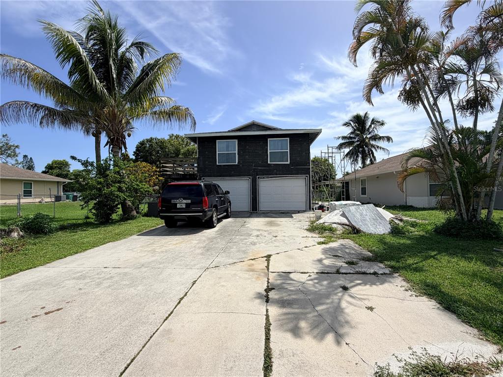 A two-story house with a dark exterior, two garage doors, and a concrete driveway — 125 4TH STREET, NAPLES, FL