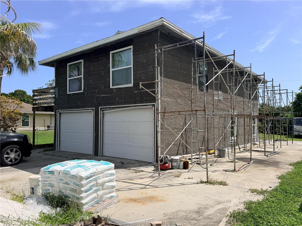 A two-story house exterior under renovation with scaffolding and stacks of construction material — 125 4TH STREET, NAPLES, FL