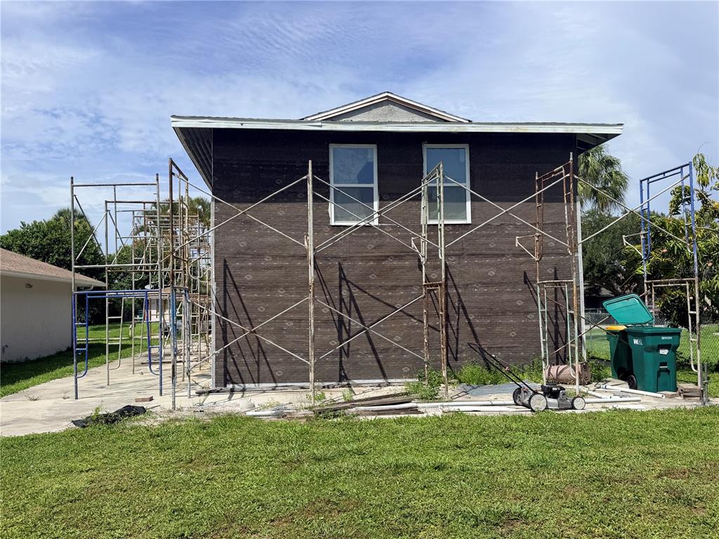 The exterior of a two-story house under construction features scaffolding and dark weather-resistant sheathing — 125 4TH STREET, NAPLES, FL