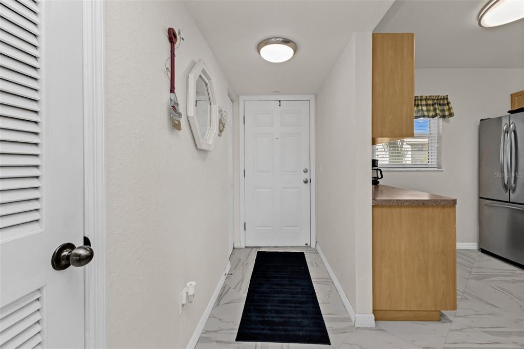 An entryway with white walls, tile flooring, a black rug, and a white front door — 175 KINGS HIGHWAY UNIT #227-B7, PUNTA GORDA, FL