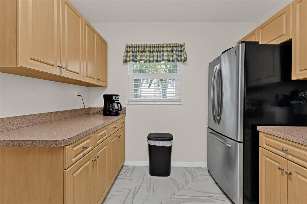 A kitchen features light wood cabinets, a stainless steel refrigerator, and a window with valance — 175 KINGS HIGHWAY UNIT #227-B7, PUNTA GORDA, FL