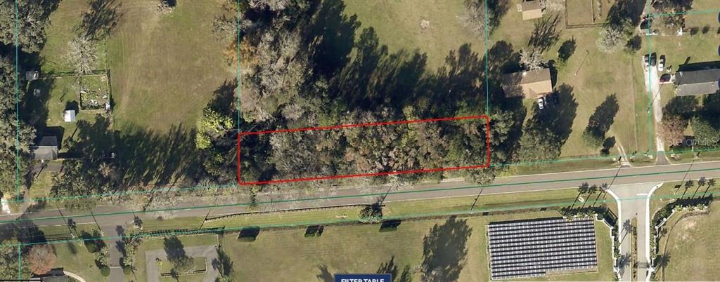 An aerial view shows a rectangular, tree-covered vacant lot outlined in red along a road — 9625 W HIGHWAY 318, REDDICK, FL