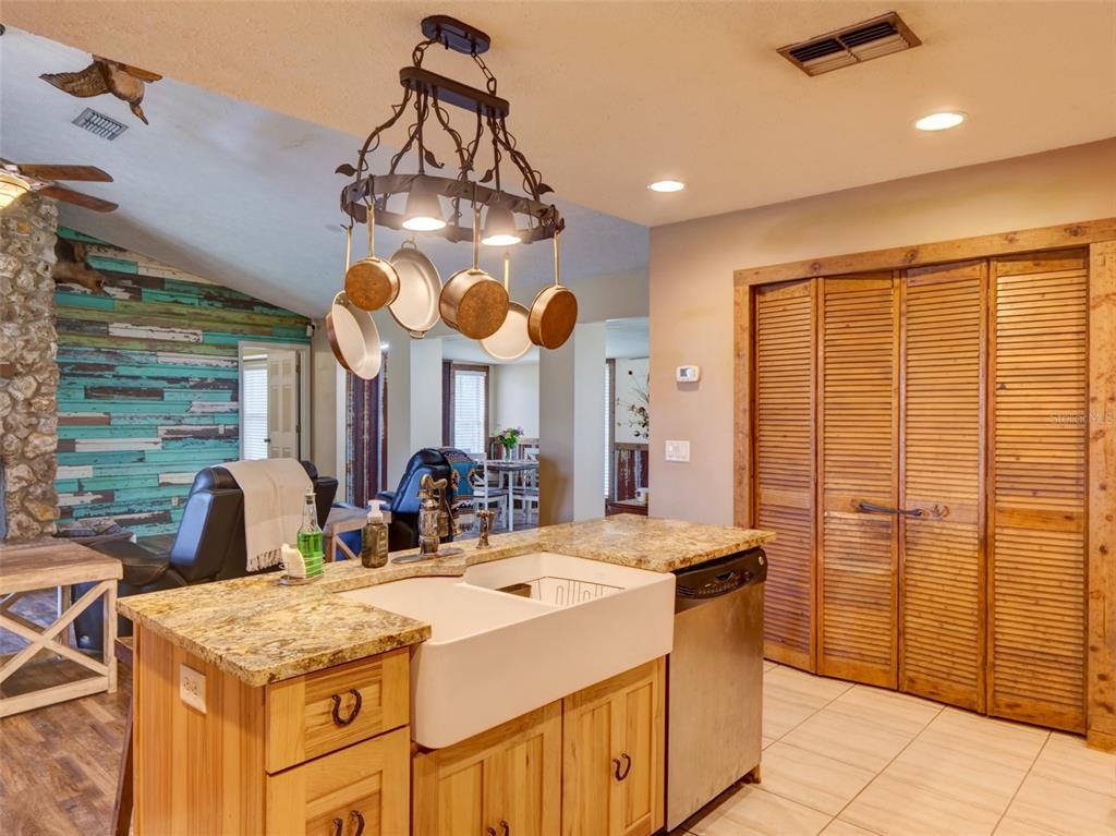 A kitchen island with a farmhouse sink sits beneath a hanging pot rack and lights — 1765 E CR 462, WILDWOOD, FL