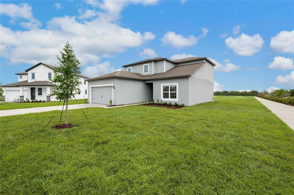 A gray two-story house with a garage and a large grassy lawn under a blue sky — 823 PONKAN COURT, BABSON PARK, FL